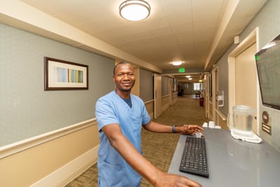 Staff member at a nursing home front desk in a hallway