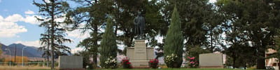 Statue surrounded by trees and flowers in an outdoor area
