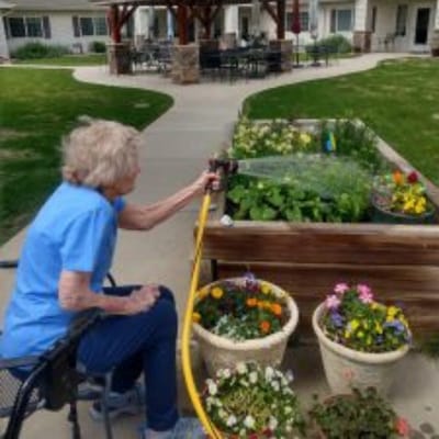 Resident watering a garden at an assisted living facility