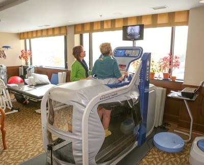 A resident using rehab equipment with staff assistance