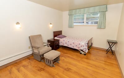 A private resident room with a bed and chair
