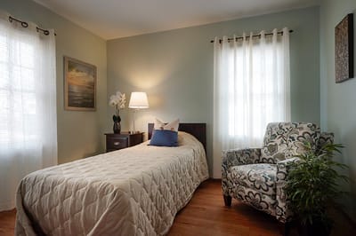 A cozy resident room with a bed and chair