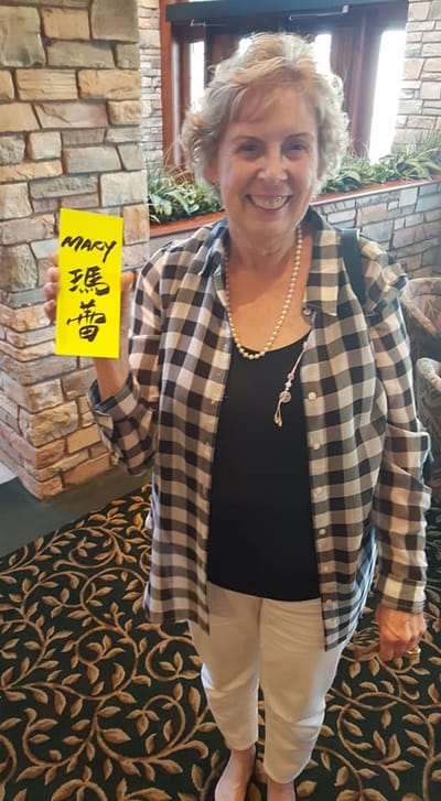 Smiling resident holding a sign in a decorated common area