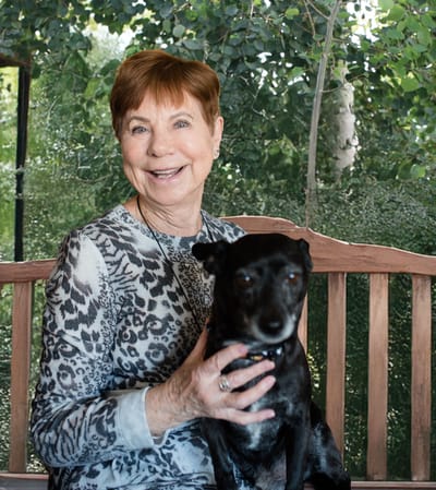 Resident smiling with a dog in a garden