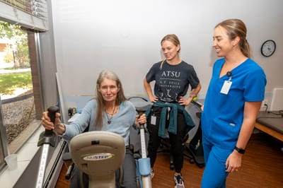 Resident engaging in physical therapy with staff assistance