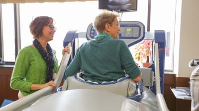 Resident using rehabilitation equipment with staff assistance