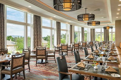 Bright dining room with large windows and tables set for dining