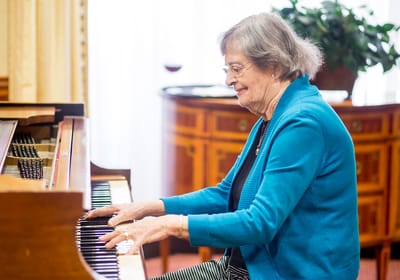 Resident playing piano in a bright common area