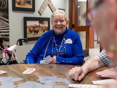 Good Samaritan Society – Loveland Village, assisted living in Loveland, CO — Smiling senior woman playing cards at a communal table