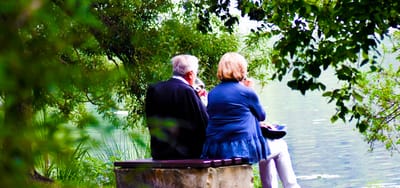Couple sitting by a tranquil lake in a garden