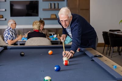 Senior playing billiards in a common area