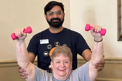 A staff member helping a resident with weights in an activity room
