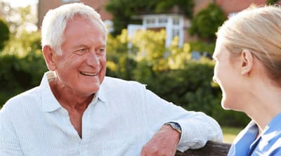 A senior man conversing with a caregiver outside