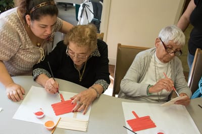 Residents engaged in an art activity with staff assistance