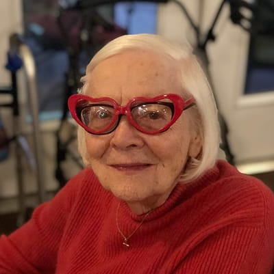 Elderly woman with heart-shaped glasses smiling