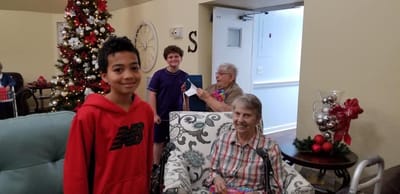 Residents and a child celebrating with gifts near a Christmas tree