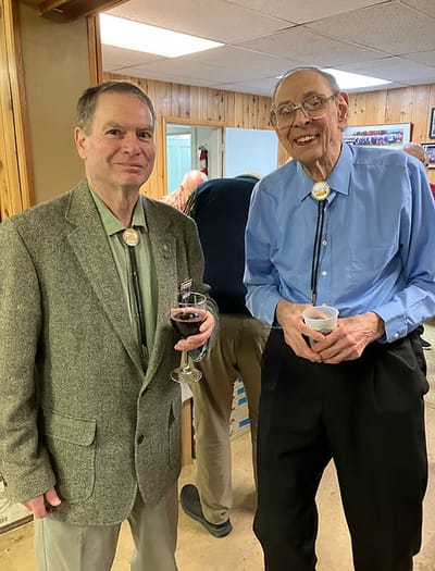 Two elderly men in a social setting with drinks