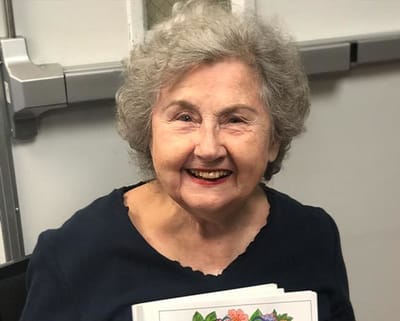 A cheerful senior resident holding a coloring book