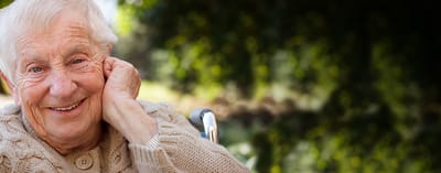 A smiling elderly woman in a cozy sweater