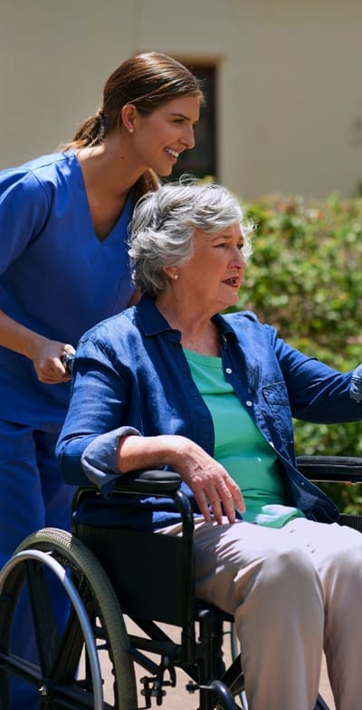 Caregiver assisting a resident in a wheelchair outdoors