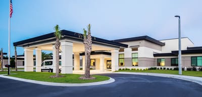 River City Center, Nursing Home in Decatur, AL — Modern senior living facility entrance with palm trees