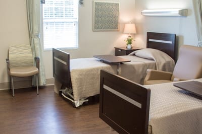 A private resident room with two beds and warm lighting