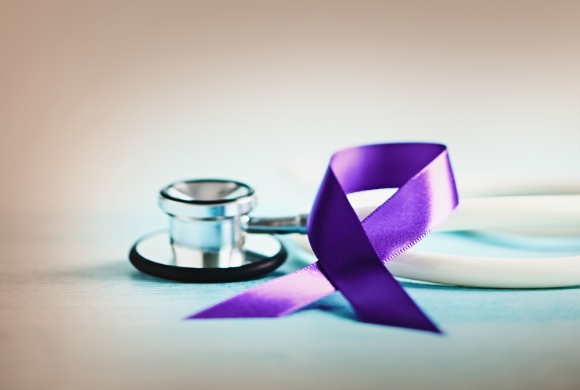 A stethoscope next to a purple awareness ribbon