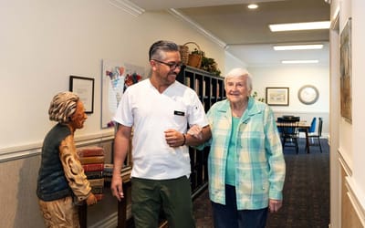 A staff member and resident walking down a hallway