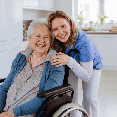 A caregiver and resident smiling together in a bright kitchen