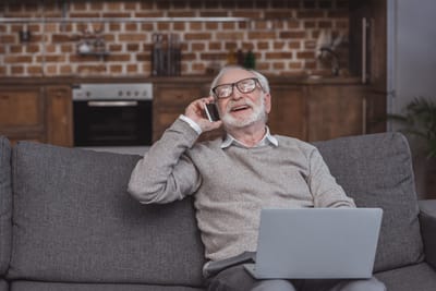 An elderly man talking on the phone in a cozy interior