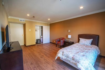 A private resident room with a bed and chair
