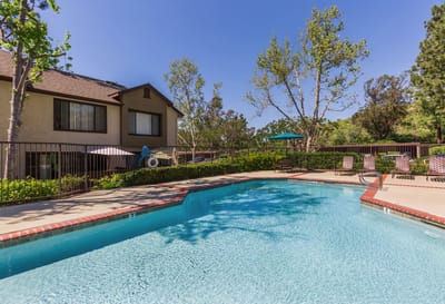 Swimming pool area outside the facility with trees and seating