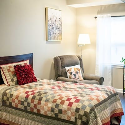 Cozy resident room with a colorful quilt and armchair