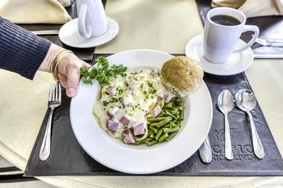 A resident served a plated meal in a dining area