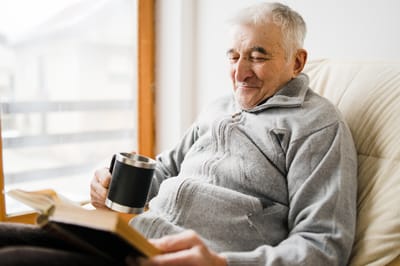 Senior man reading a book while enjoying coffee