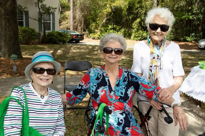 Three senior women smiling at an outdoor event