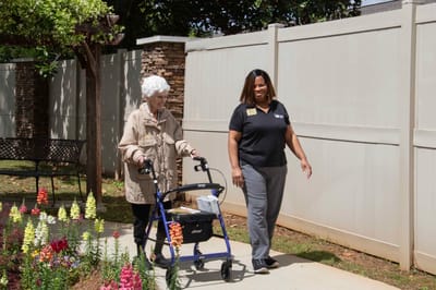 Caregiver assisting a resident in a garden area