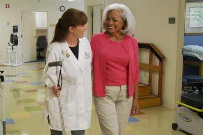 A staff member and resident interacting in a facility hallway