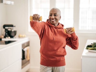 Resident exercising with dumbbells in a bright kitchen