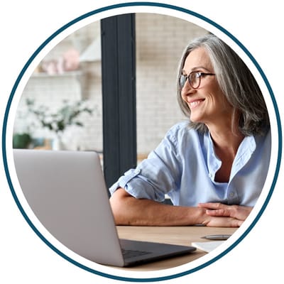 Senior woman smiling while using a laptop