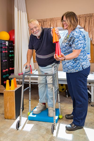 Resident participating in therapy with staff assistance