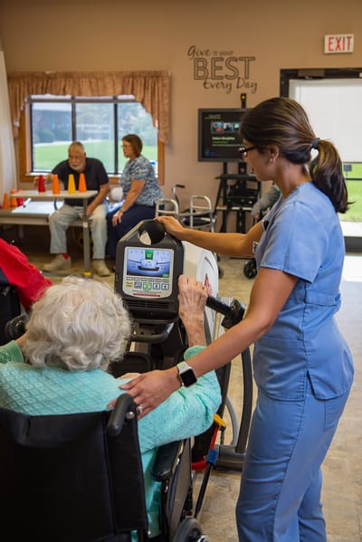 Therapist assisting a resident with equipment in a therapy room