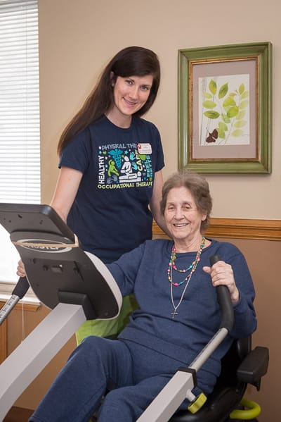 Staff assisting a resident with exercise equipment
