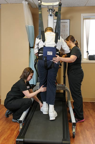 Staff assisting resident with rehabilitation equipment