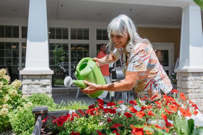 Resident gardening in a flower bed with a watering can