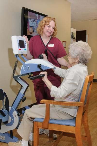 Staff assisting a resident with exercise equipment