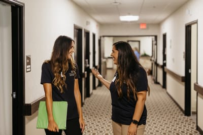 Two staff members chatting in a hallway