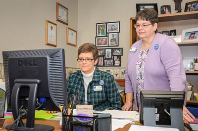 Staff assisting at a computer in an office setting