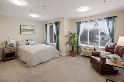 Cozy and well-lit resident room with a bed and seating