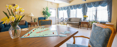 Majestic Care of Bedford, Nursing Home in Bedford, IN — Bright activity room with a Monopoly game and flowers